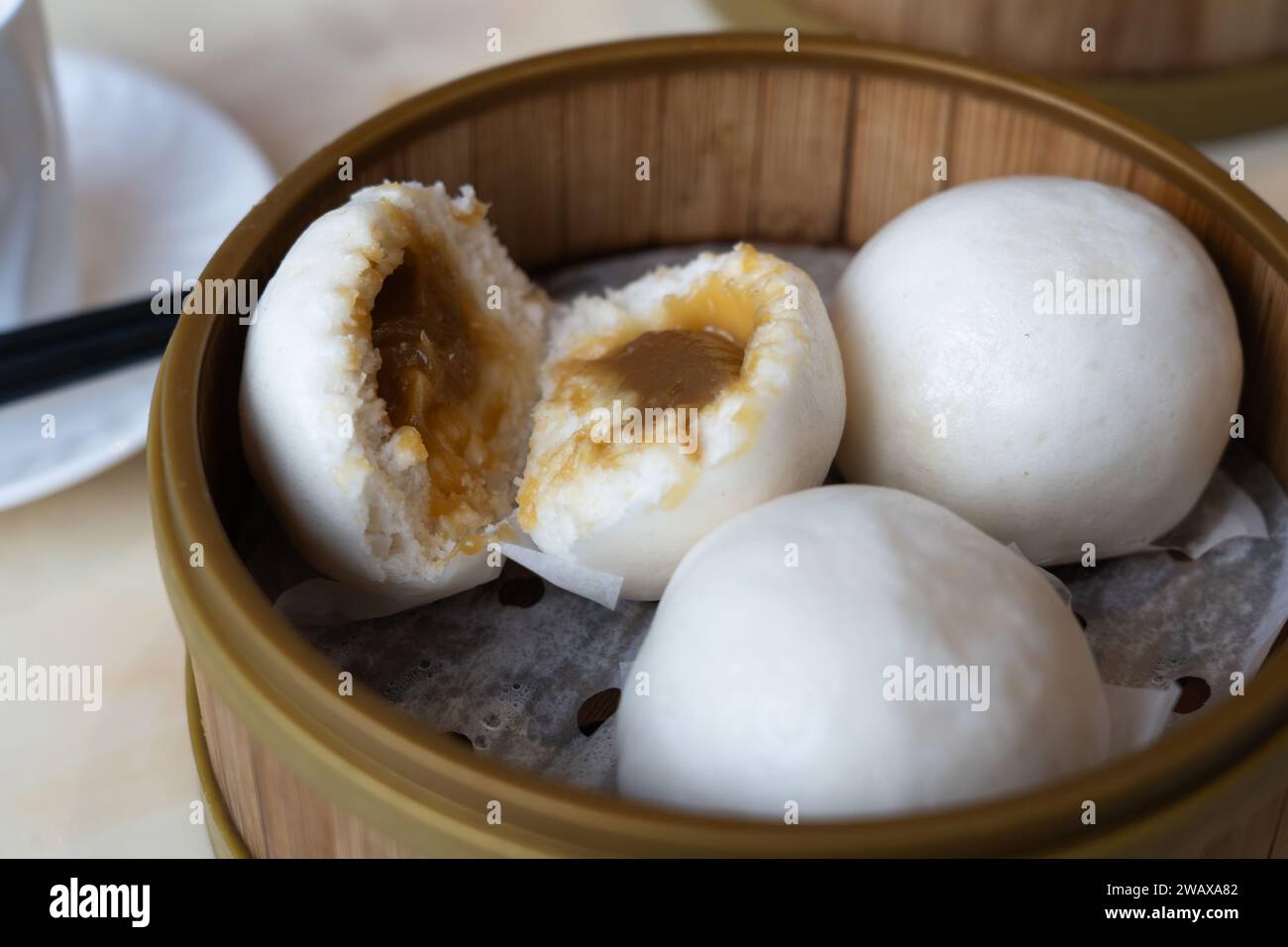 Dim sum cantonese - focaccine di bao lin yong (o yung) con pasta di semi di loto - servite in un piroscafo di bambù, Regno Unito Foto Stock