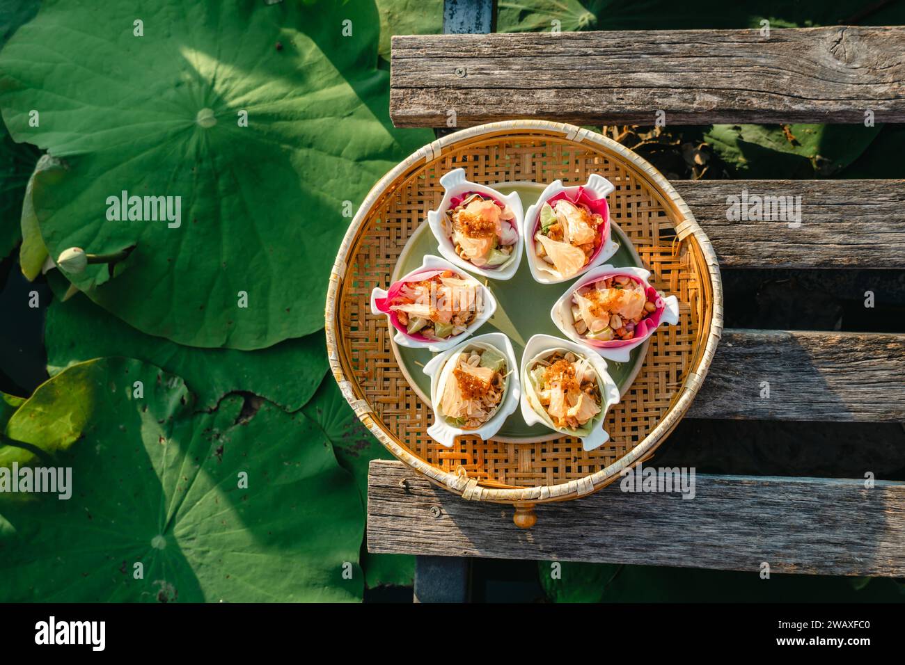 Tradizionale spuntino thailandese chiamato Miang Kham, saporito petalo di loto rosa avvolto (saporito petalo di fior di loto avvolto). Delizioso e fresco Lotus Petal Savory Foto Stock