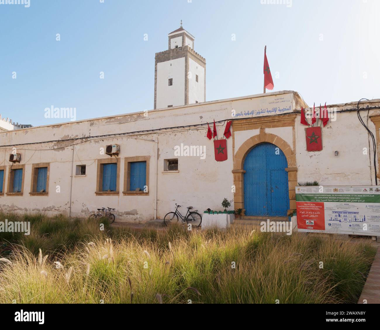 Albergo con porte blu e torre con bicicletta e giardino sovrastato nella storica medina nella città di Essaouira, Marocco. 7 gennaio 2024 Foto Stock
