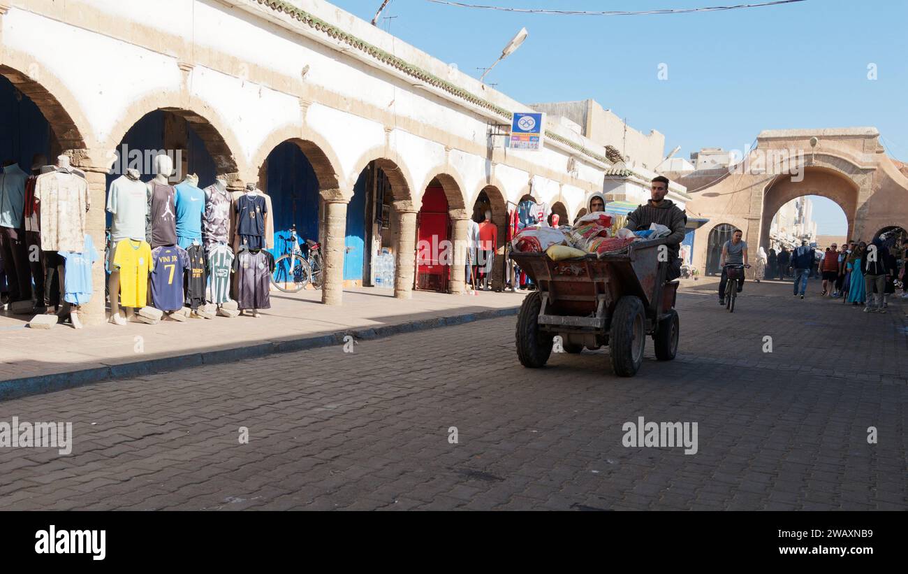 La strada principale con arco e negozio di abbigliamento come camion ribaltabile è guidata nella città di Essaouira, in Marocco. 7 gennaio 2024 Foto Stock