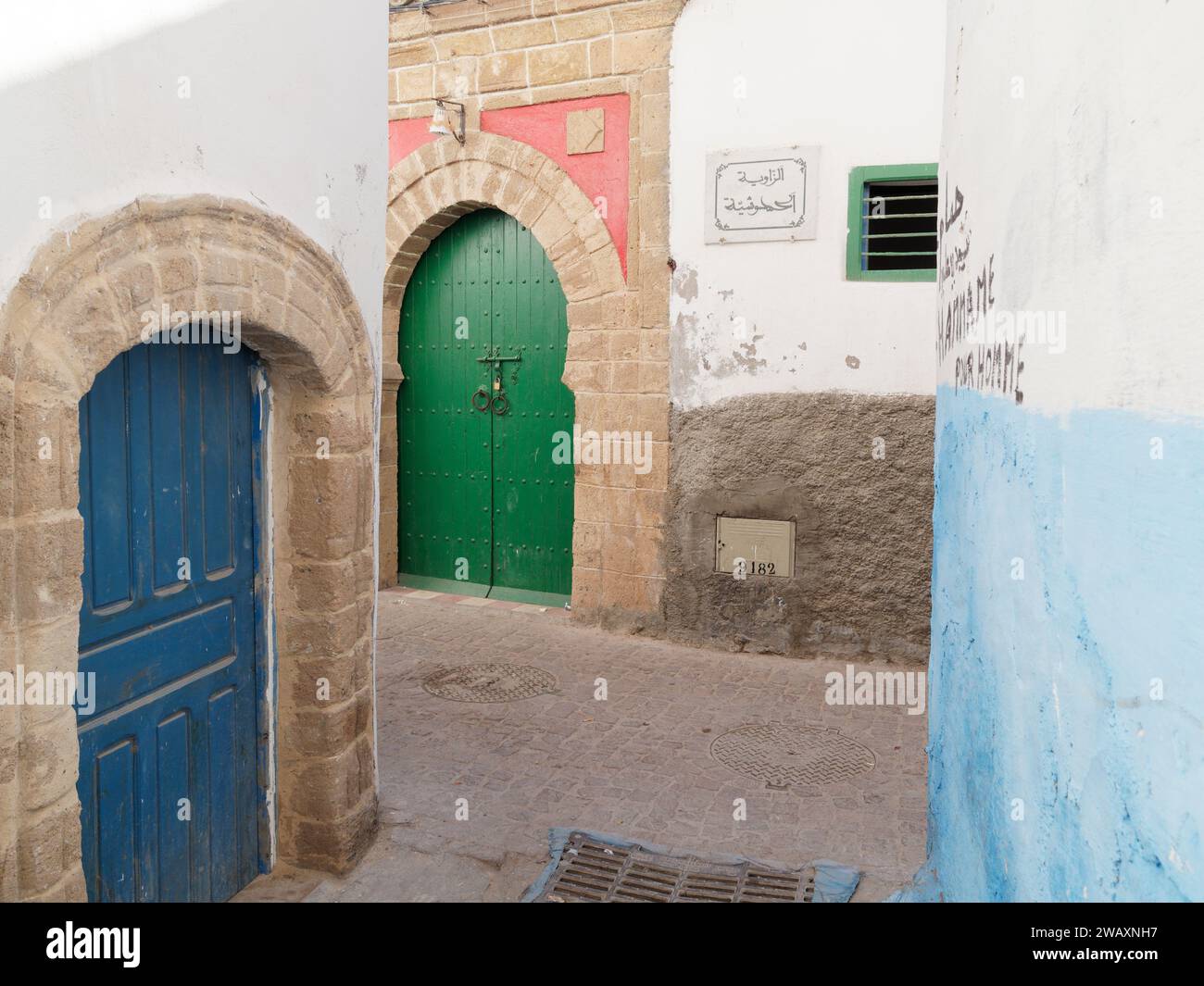 Strada stretta e colorata con porte blu e verdi e mura blu nella storica medina della città di Essaouira, in Marocco. 7 gennaio 2024 Foto Stock