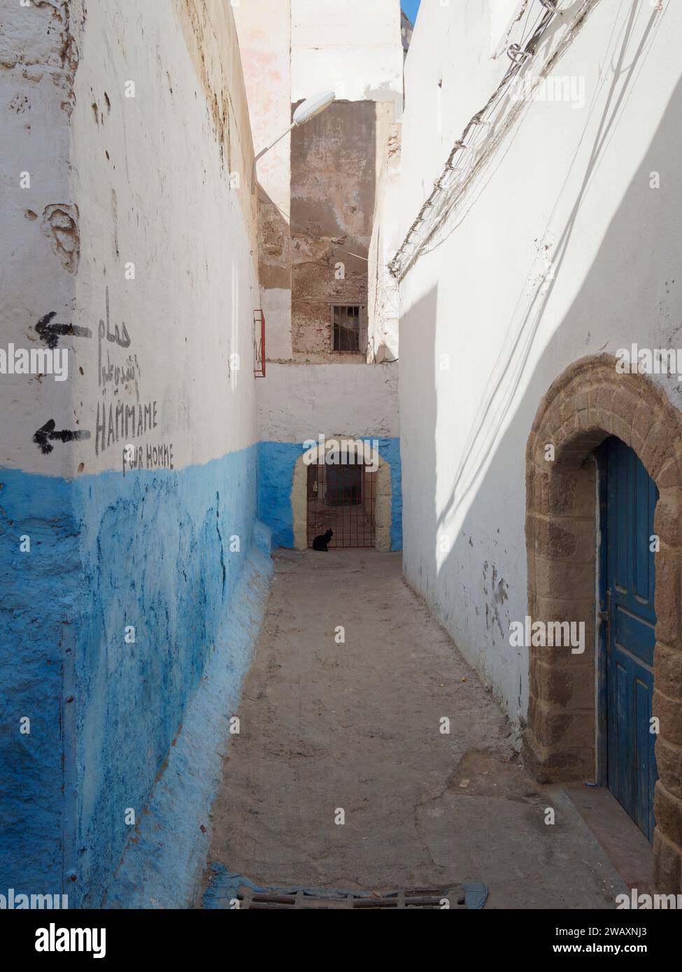 Strada stretta e colorata con mura blu e insegna hammam nella storica medina della città di Essaouira, in Marocco. 7 gennaio 2024 Foto Stock
