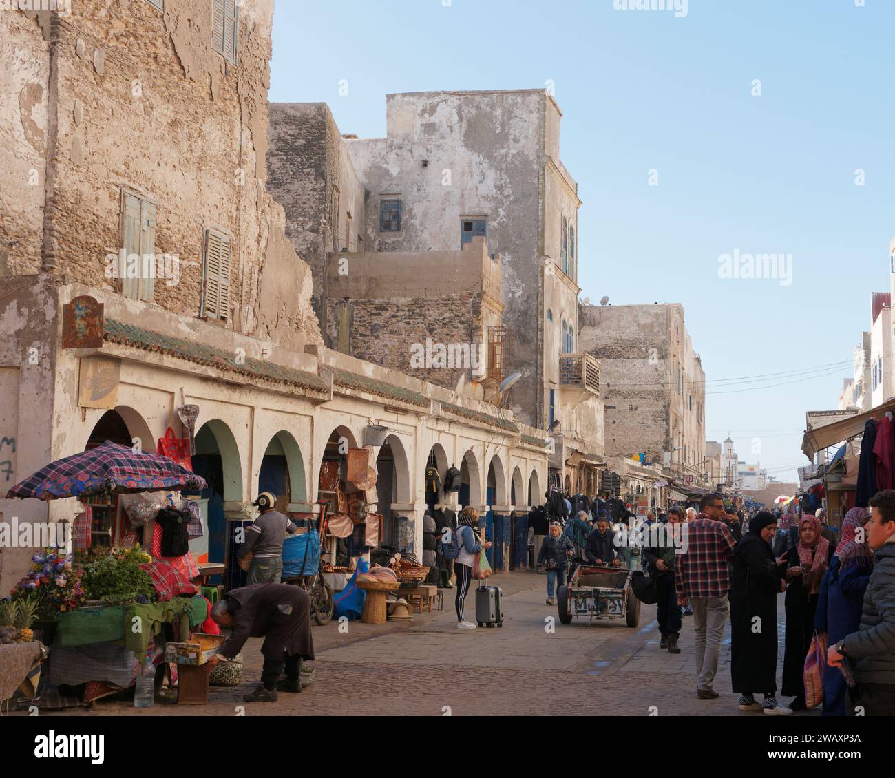 Strada principale trafficata con mercato ed edifici ingombranti nella storica medina della città di Essaouira, Marocco. 7 gennaio 2024 Foto Stock