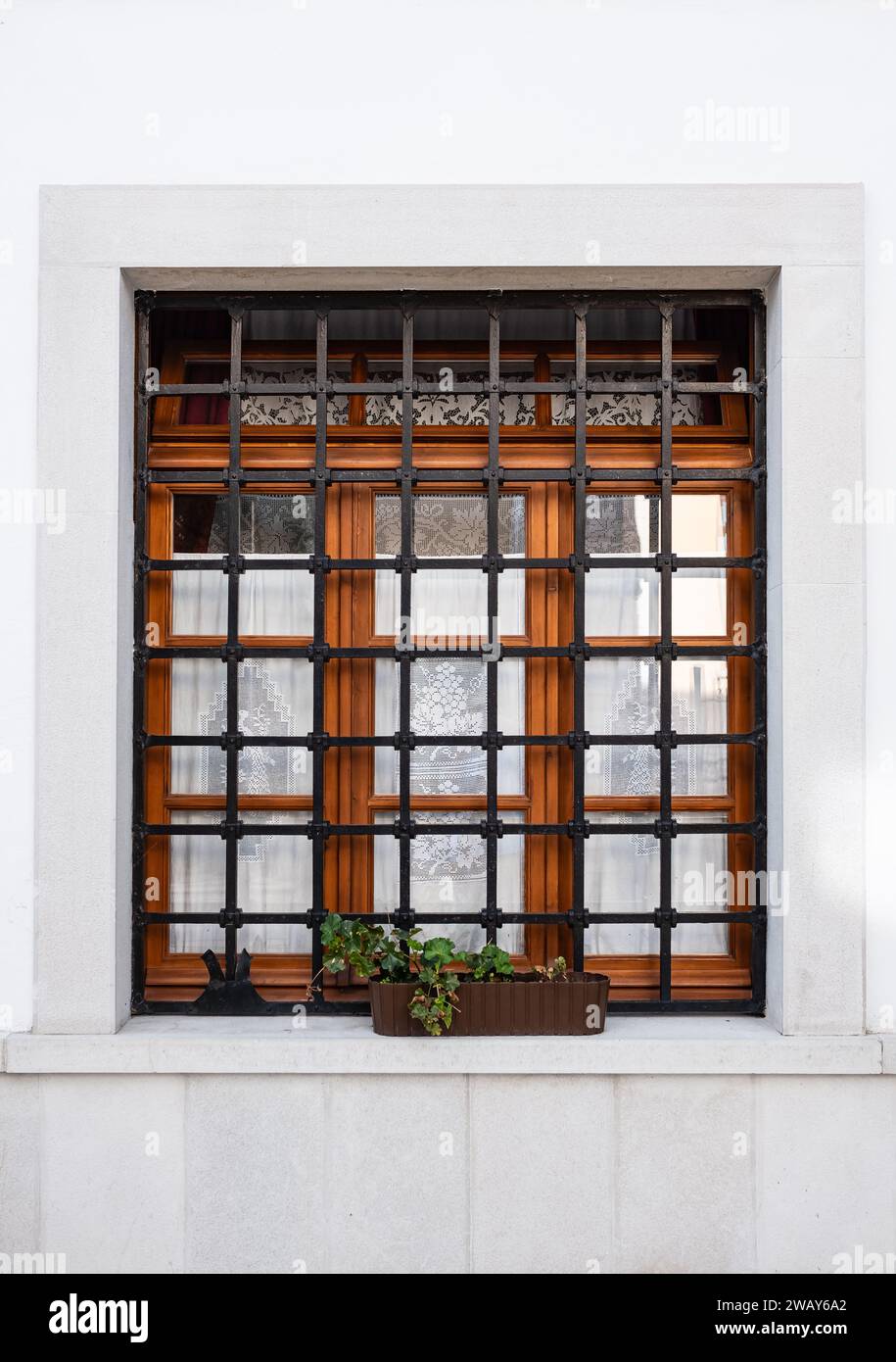 Finestra con griglia di ferro su parete bianca. Reticolo sulla finestra, architettura di una casa di campagna. Barre delle finestre. Barre montate sopra il finestrino. Nessuno, puzza Foto Stock