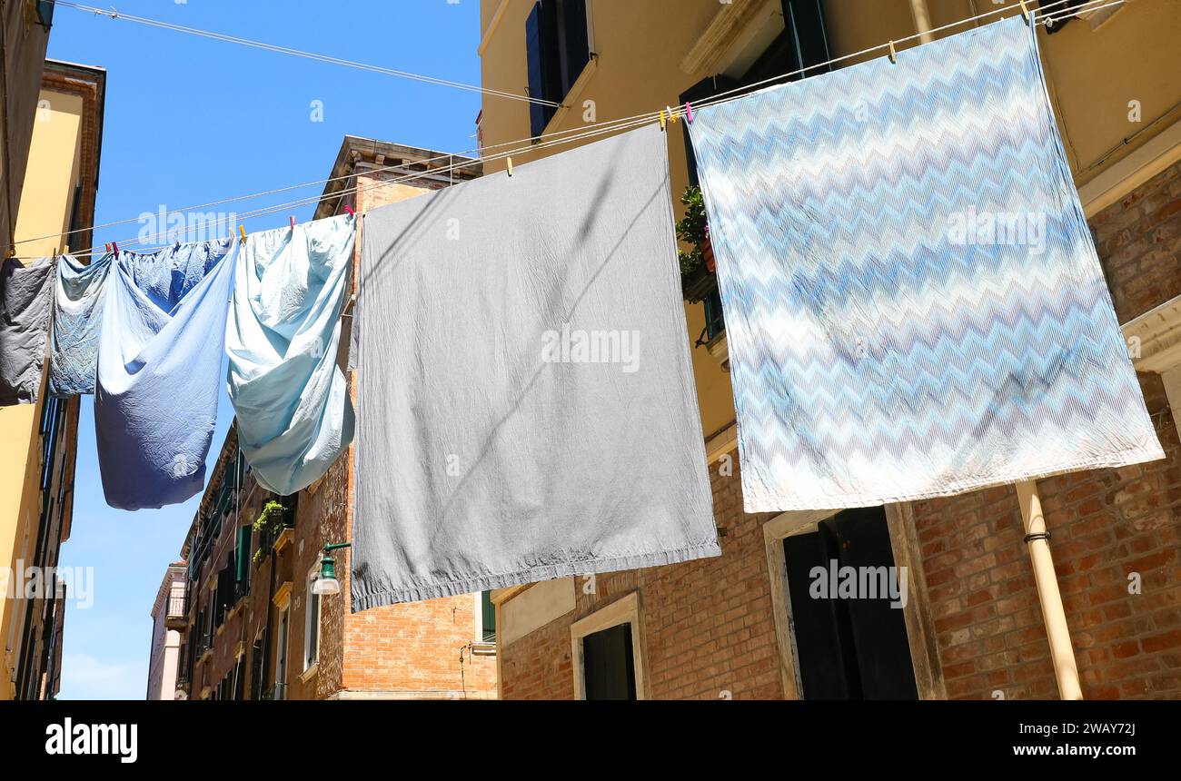 molti vestiti si appendevano al sole con lenzuola e federe in un vicolo Foto Stock