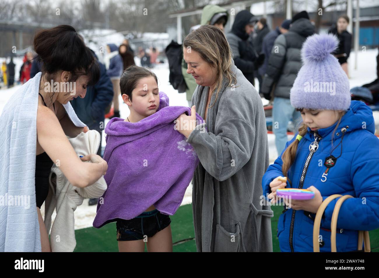 Kiev, Ucraina. 6 gennaio 2024. Le donne aiutano un ragazzo ad asciugarsi dopo aver nuotato nelle fredde acque del fiume Dnipro in occasione della celebrazione dell'Epifania a Kiev. L'Ucraina celebra l'Epifania il 6 gennaio per la prima volta quest'anno, seguendo il calendario occidentale, partendo dalla tradizione della Chiesa ortodossa russa di celebrarla il 19 gennaio. Durante l'Epifania, alcune persone credono che le acque abbiano speciali proprietà curative e possano essere usate per curare varie malattie, e molti di loro fanno il bagno nell'acqua come parte della celebrazione dell'Epifania. (Immagine di credito: © Oleksii Chumachenko/SOPA IM Foto Stock