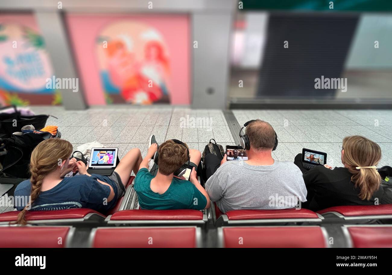 Famiglia che aspetta all'aeroporto. Dispositivi tecnologici, varie piattaforme per l'intrattenimento pre-volo. Tempo di attesa prima dell'imbarco. 07-04-2023. Foto Stock