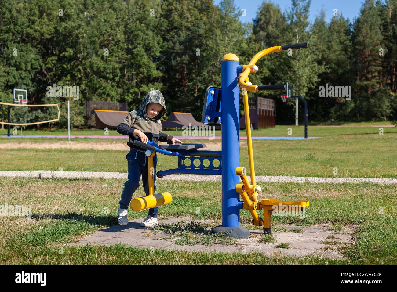 Un bambino con una felpa con cappuccio si familiarizza con un dispositivo da allenamento su un terreno di allenamento all'aperto. Foto Stock