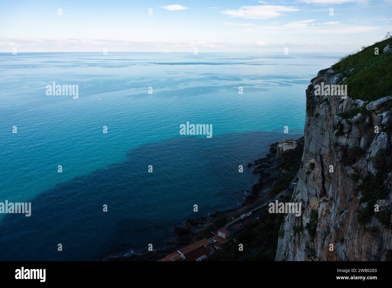 Vista dall'alto su una scogliera ripida e sul mare blu a Cefalù, Sicilia, Italia Foto Stock