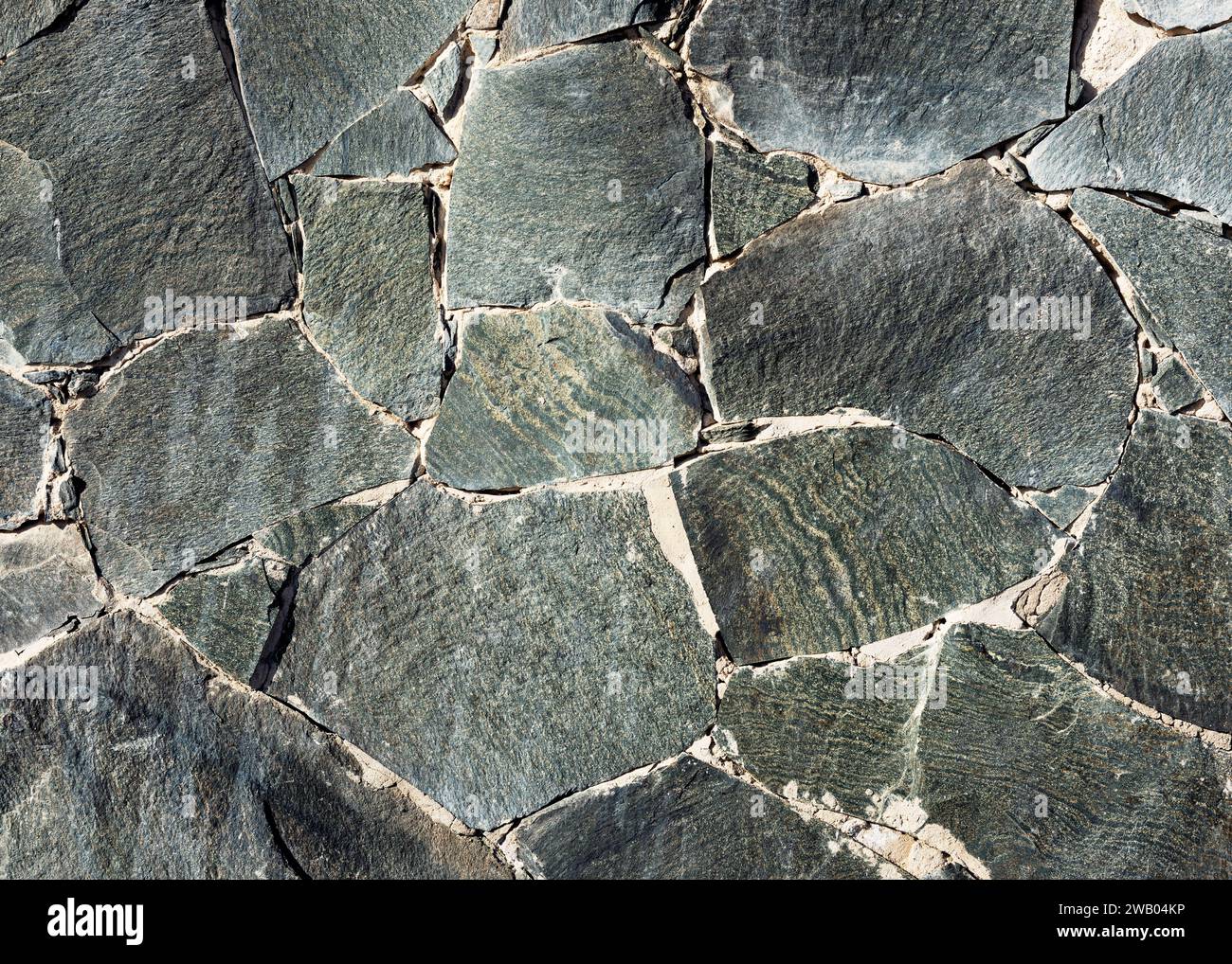 Mosaico rustico grigio scuro e nero stonewall di diverse dimensioni e forme. Elementi decorativi vintage. Foto Stock