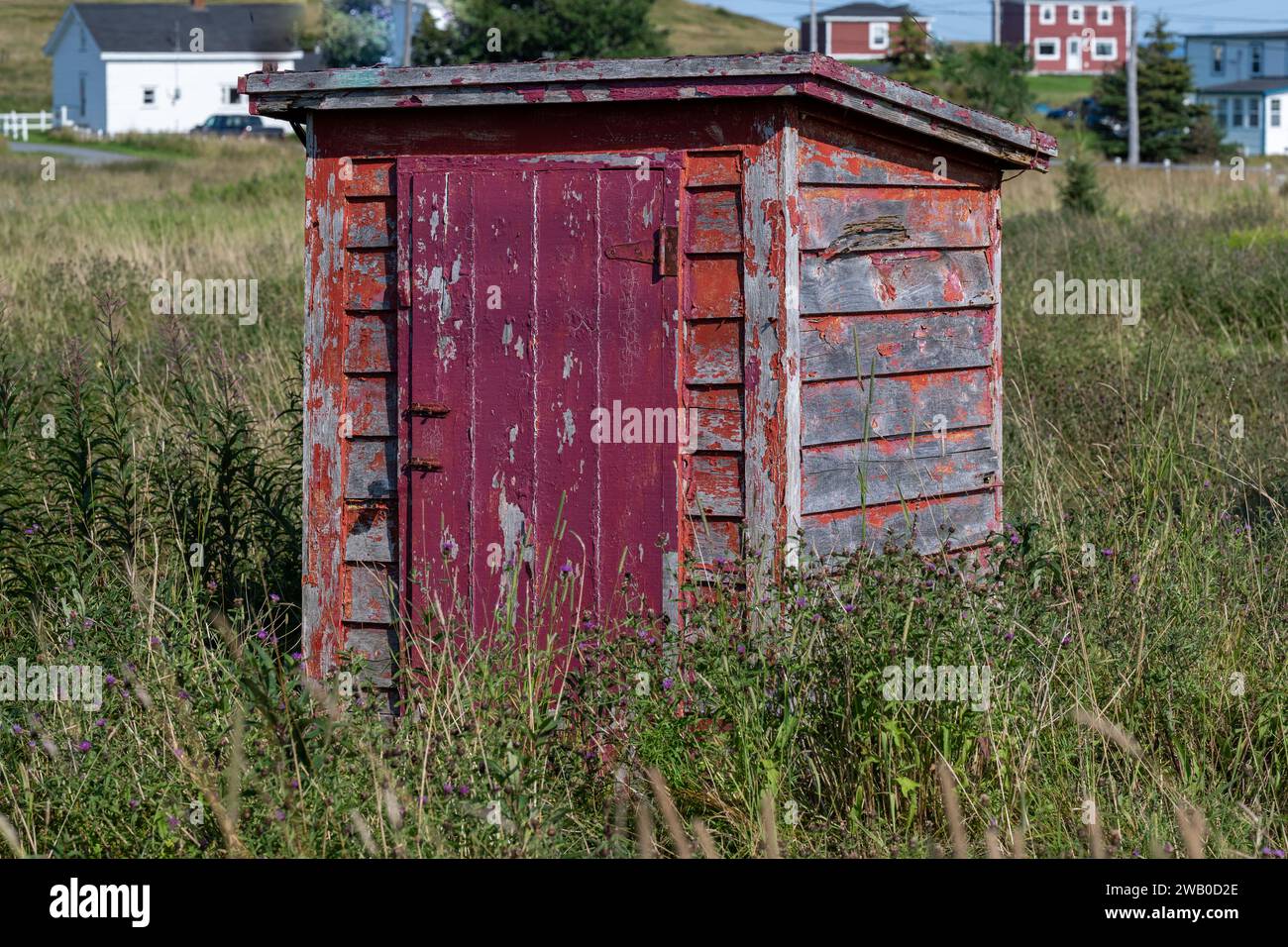 L'esterno di un bagno vintage rosso brillante o privato. La vecchia toilette esterna in legno ha un rivestimento in legno alle pareti, una maniglia o una serratura vintage Foto Stock