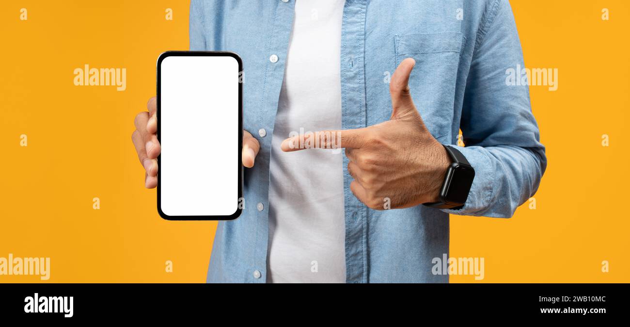 Un uomo con una camicia in denim punta su uno smartphone portatile con uno schermo bianco vuoto Foto Stock