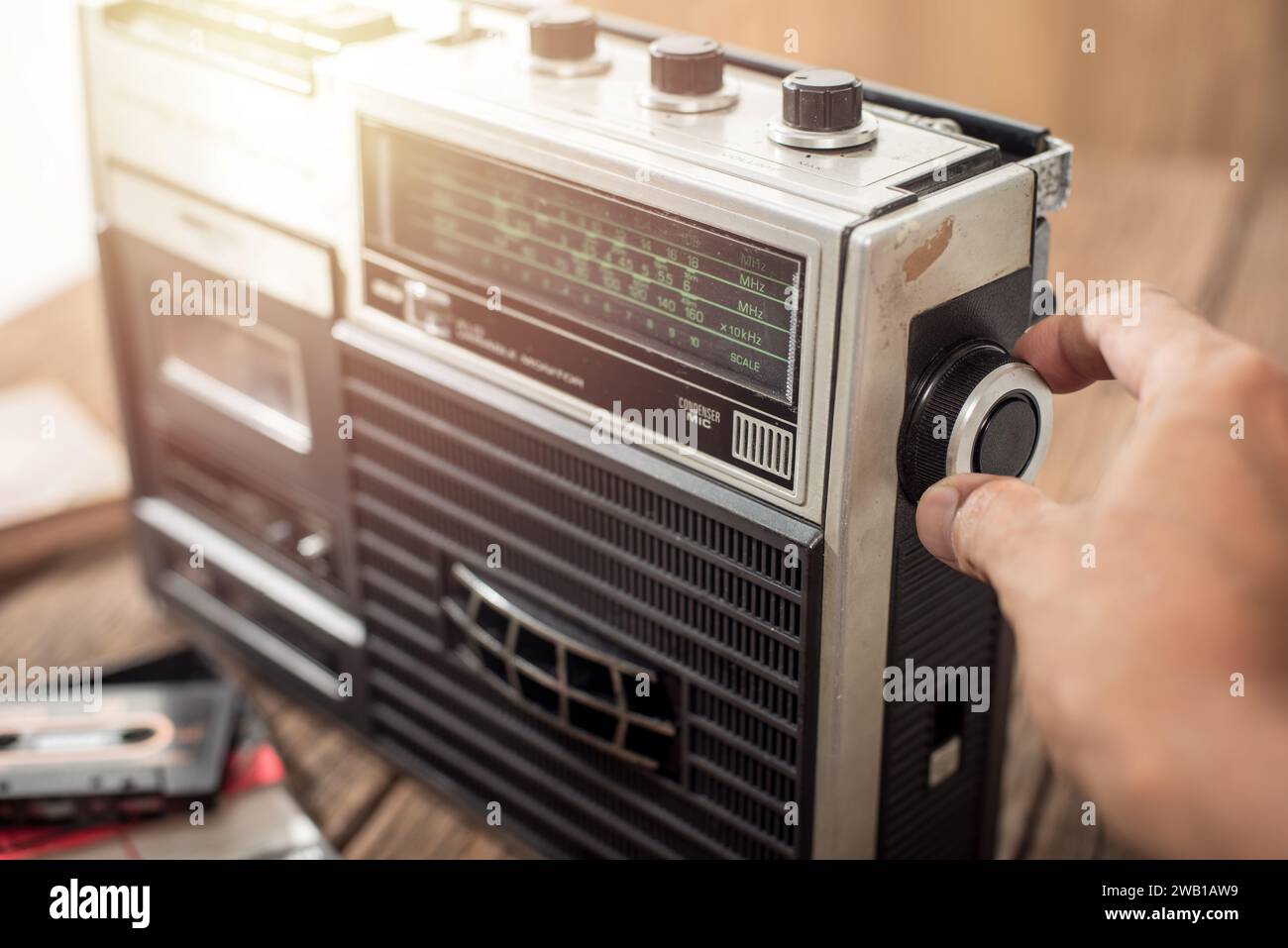 L'uomo che gira la manopola della radio vintage. Concetto di ascolto musicale. Foto Stock