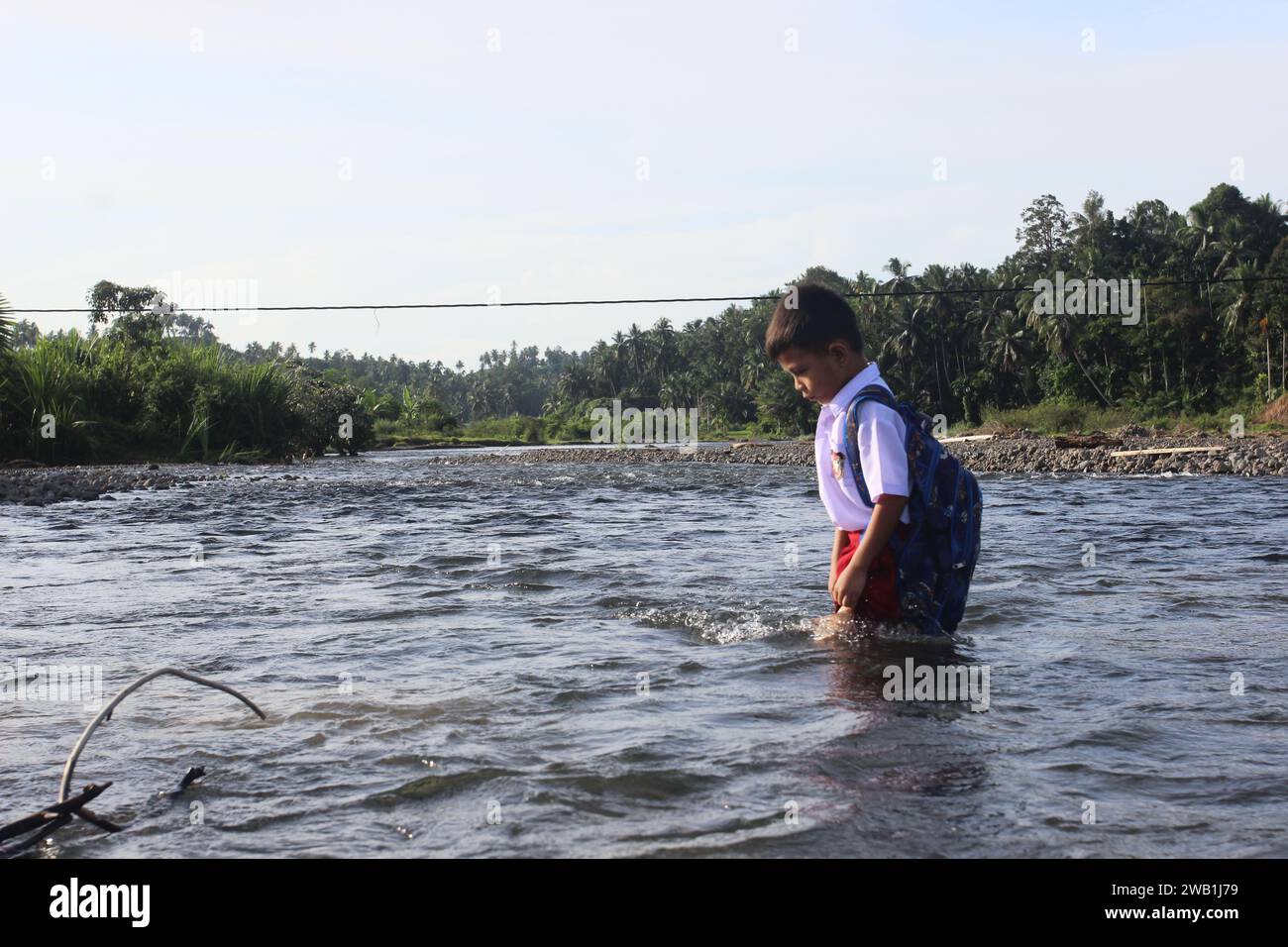 Il ritratto degli studenti indonesiani che camminano per un chilometro per andare a scuola, attraversando un fiume nel distretto di Sungai Limau, nella reggenza di Padang Pariaman, nella provincia di Sumatra Occidentale, l'8 gennaio 2024. Il governo indonesiano ha stanziato un budget per l'istruzione di 660.8 trilioni di Rp60.8 miliardi, ovvero il 20% nel bilancio dello Stato 2024, ha dichiarato Isa Rachmatarwata, Direttore generale del bilancio del Ministero delle Finanze indonesiano, l'11 ottobre 2023. Foto Stock