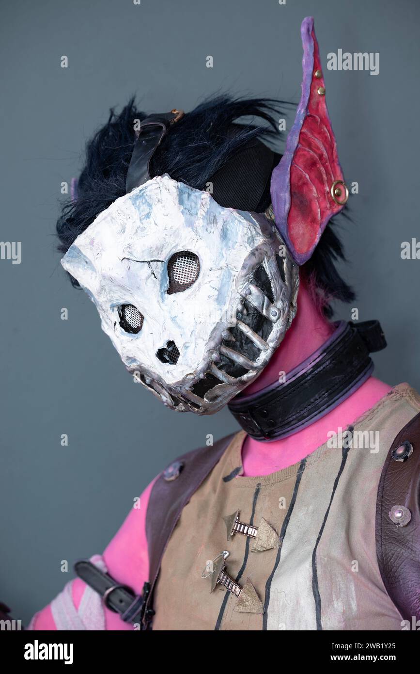 Una cosplayer femminile vestita da mostro rosa con una maschera cranica Foto Stock