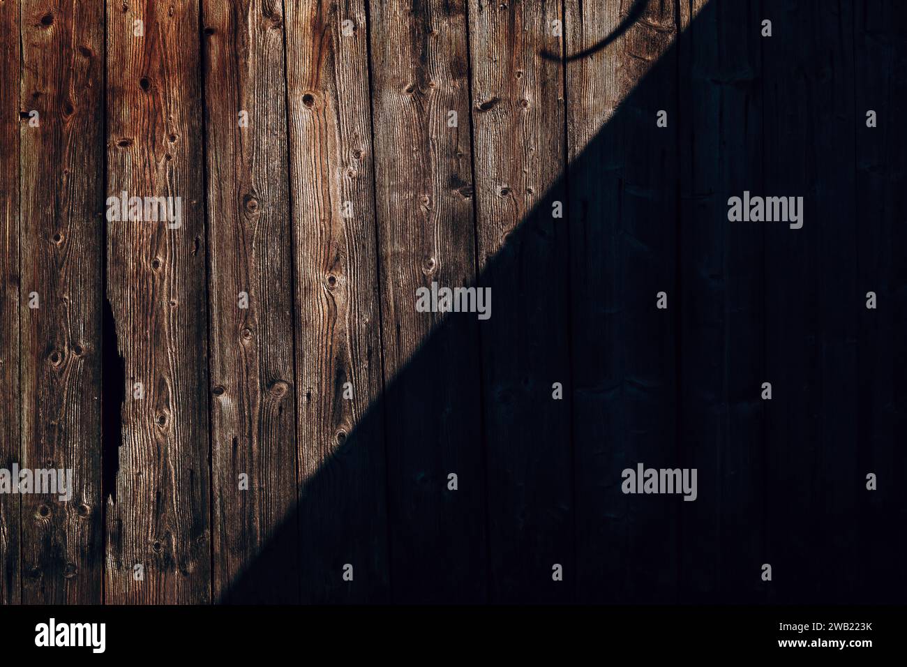 Parete rustica in legno con ombra diagonale che crea un motivo complesso sullo sfondo e un elemento di design con struttura superficiale usurata Foto Stock