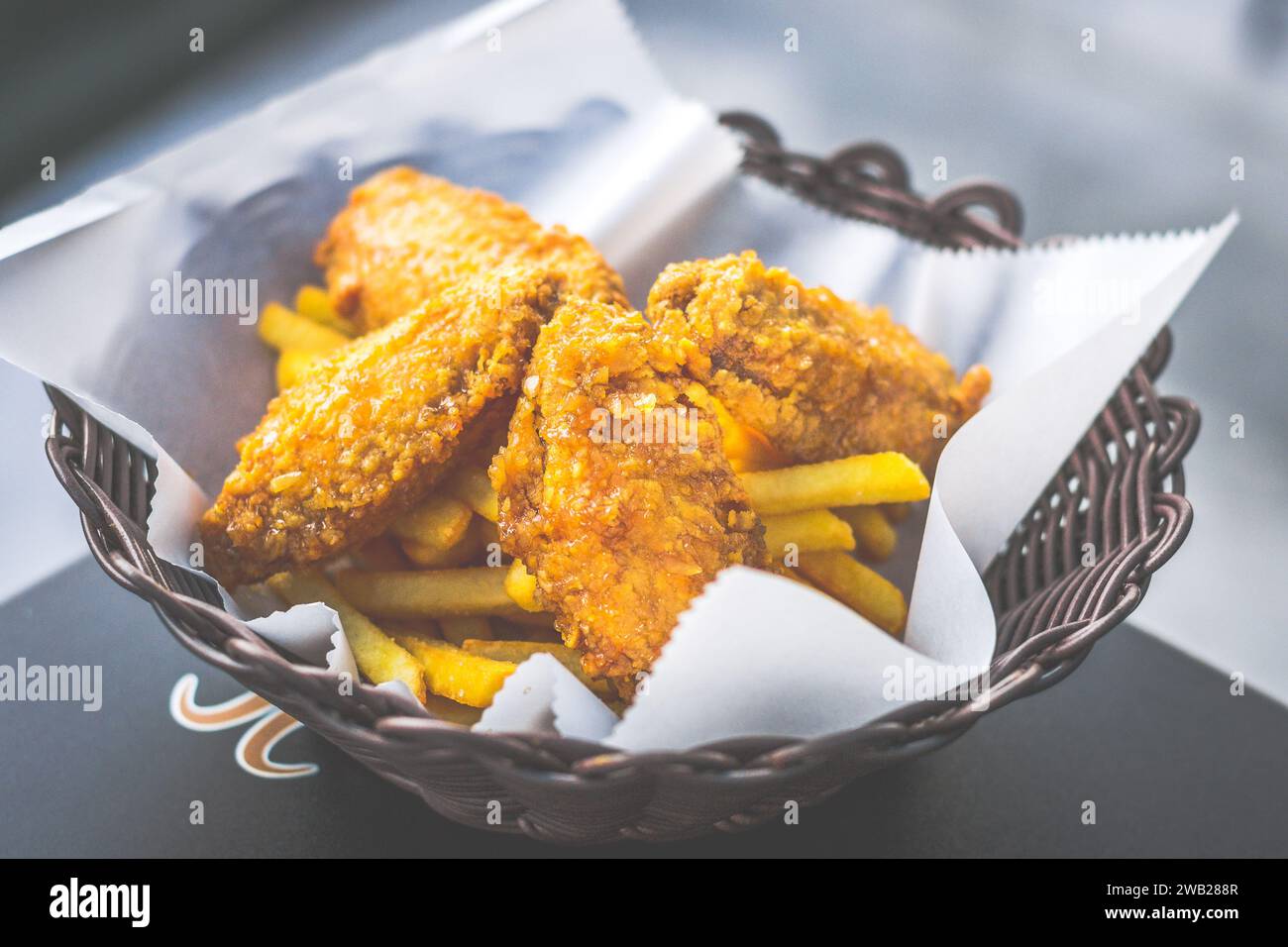 ali di pollo fritte dorate croccanti servite in un cestino con patatine fritte Foto Stock