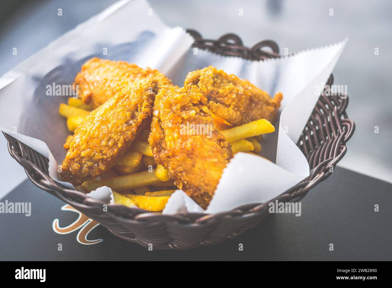 ali di pollo fritte dorate croccanti servite in un cestino con patatine fritte Foto Stock