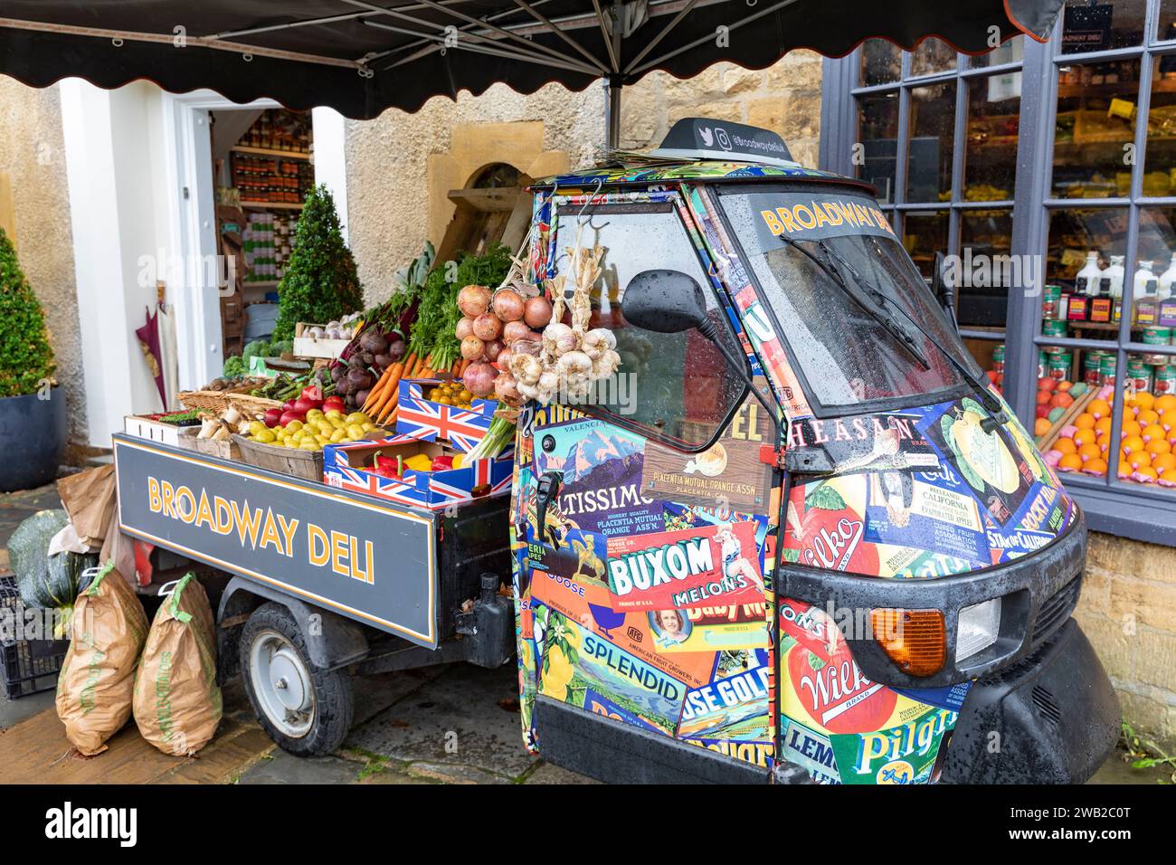 Broadway Village in the Cotswolds, Broadway Deli store che vende generi alimentari e verdure, Worcestershire, Inghilterra, Regno Unito, con un furgone di scimmia piaggio italiano Foto Stock