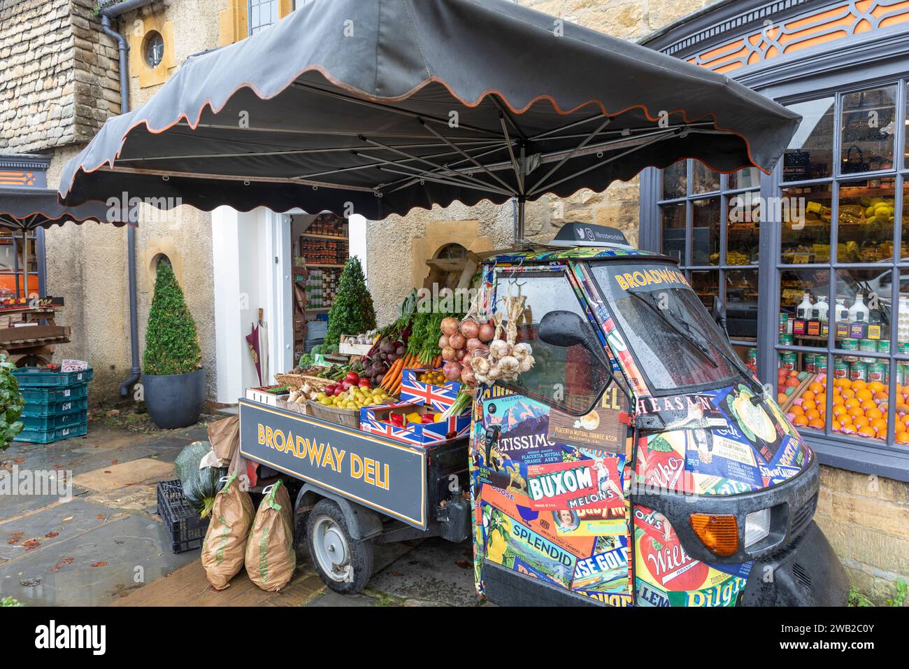 Broadway Village in the Cotswolds, Broadway Deli store che vende generi alimentari e verdure, Worcestershire, Inghilterra, Regno Unito, con un furgone di scimmia piaggio italiano Foto Stock