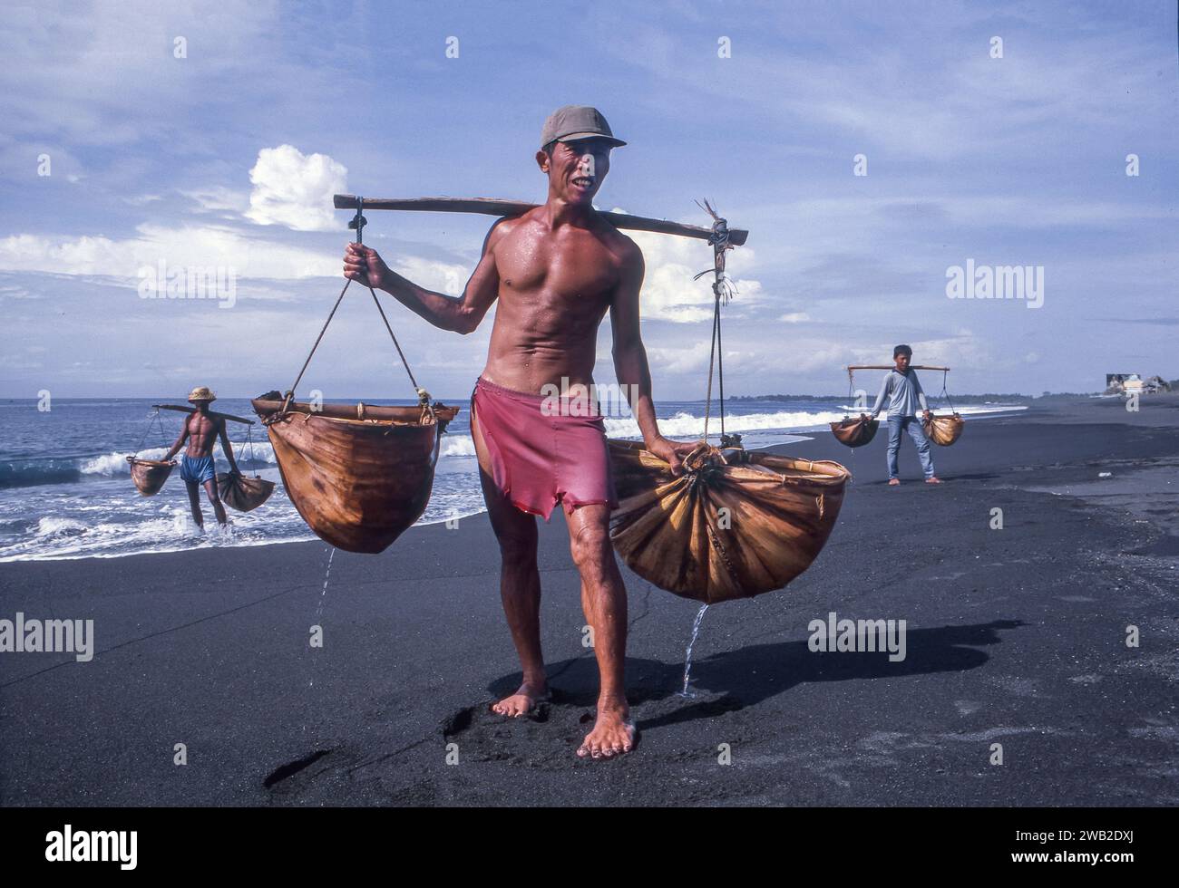 Indonesia, Giava. Gli uomini hanno raccolto acqua di mare per asciugarsi e produrre sale. Foto Stock