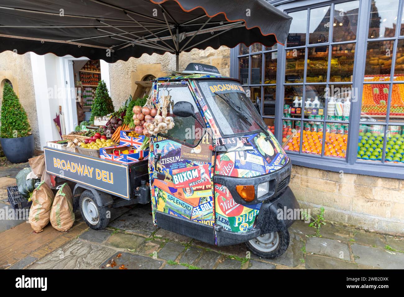 Broadway Village in the Cotswolds, Broadway Deli store che vende generi alimentari e verdure, Worcestershire, Inghilterra, Regno Unito, con un furgone di scimmia piaggio italiano Foto Stock