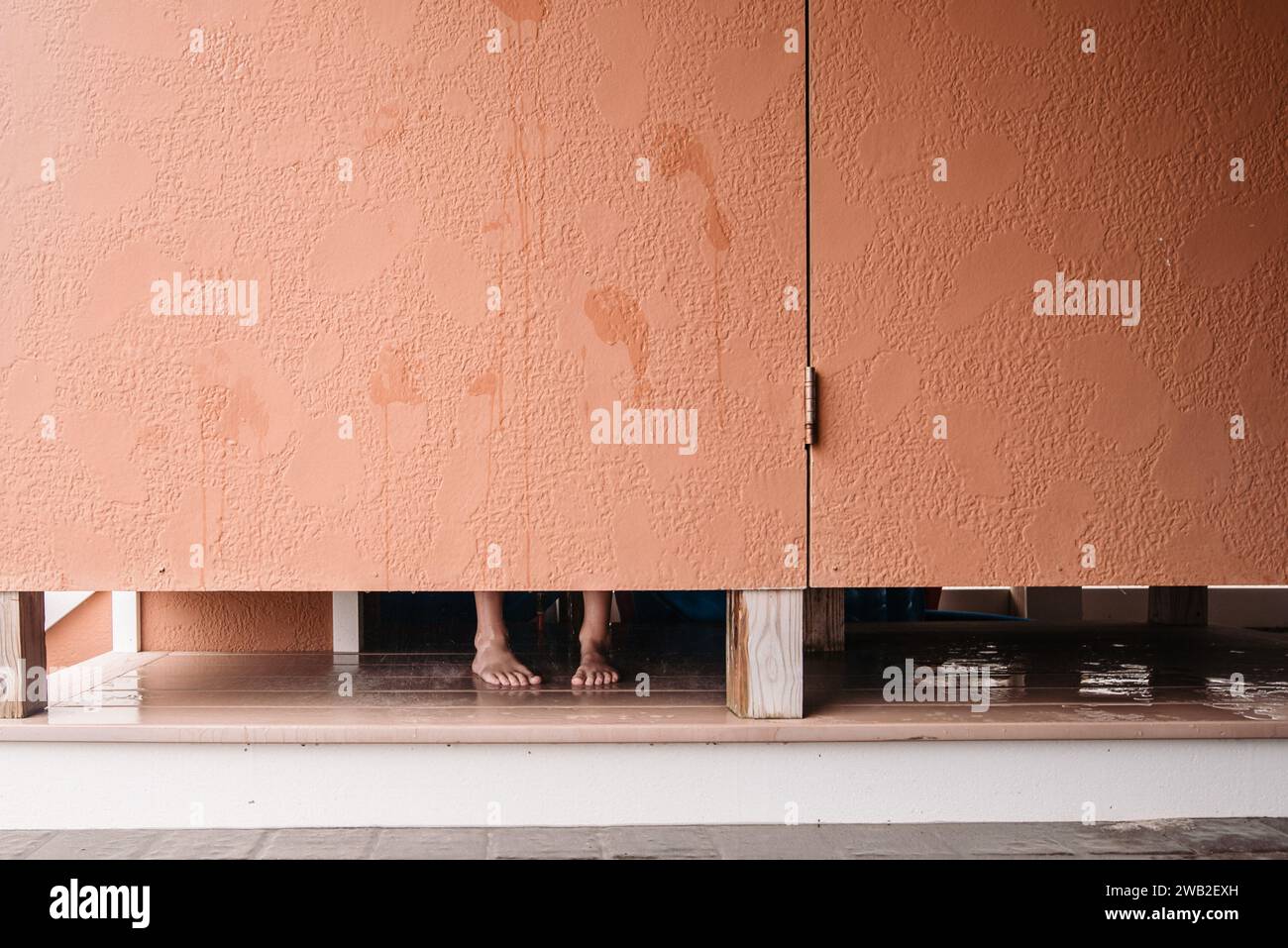 Piedi visibili sotto la porta della doccia esterna Foto Stock