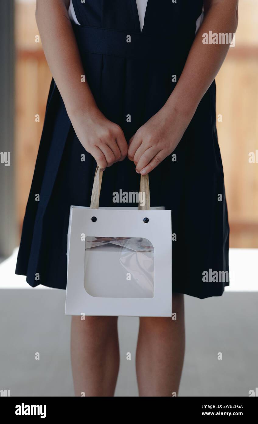 Studentessa che tiene in mano una borsa regalo bianca con un regalo all'interno Foto Stock