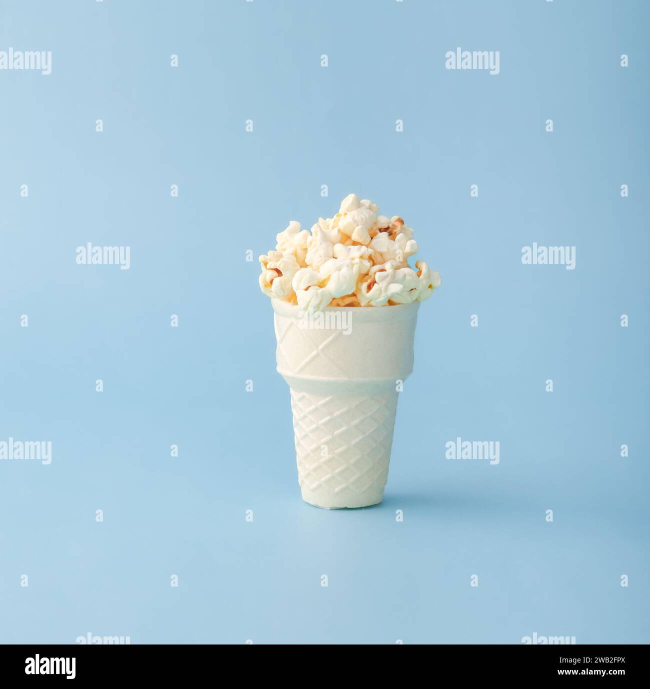 Cono waffle riempito con popcorn su sfondo blu Foto Stock