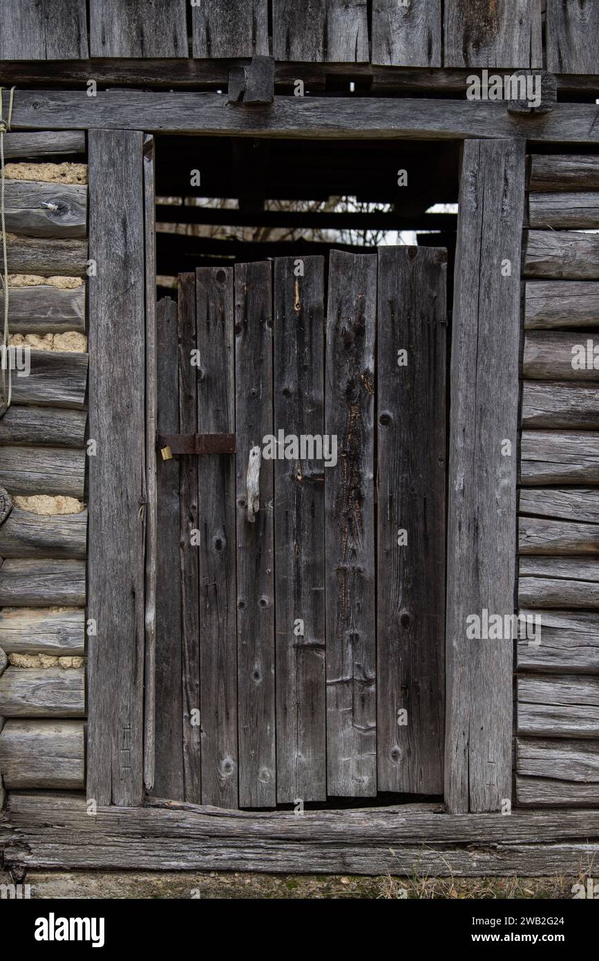 Sunja, Croazia, 05,04,2021: Vecchia porta rustica in legno sul muro della casa rurale. Foto Stock