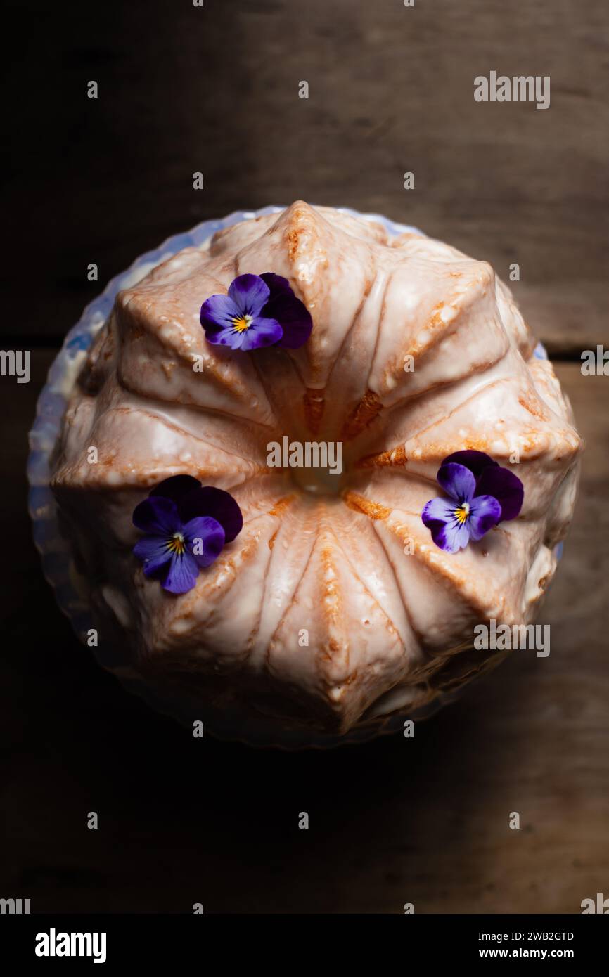 Bundt cake con glassa al limone con pansies viola Foto Stock