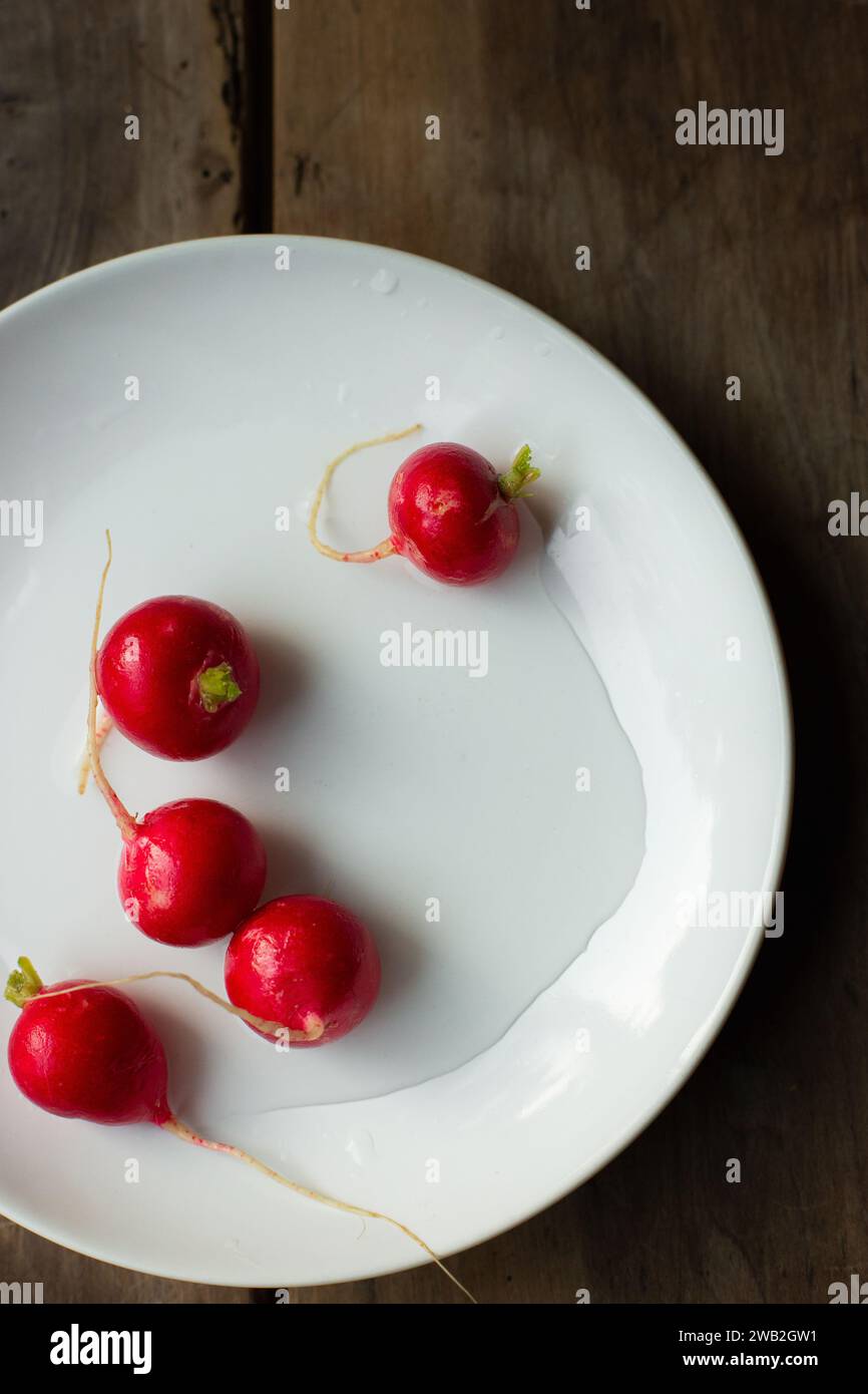 Brillanti, freschi, rossi si irradiano su un piatto bianco Foto Stock