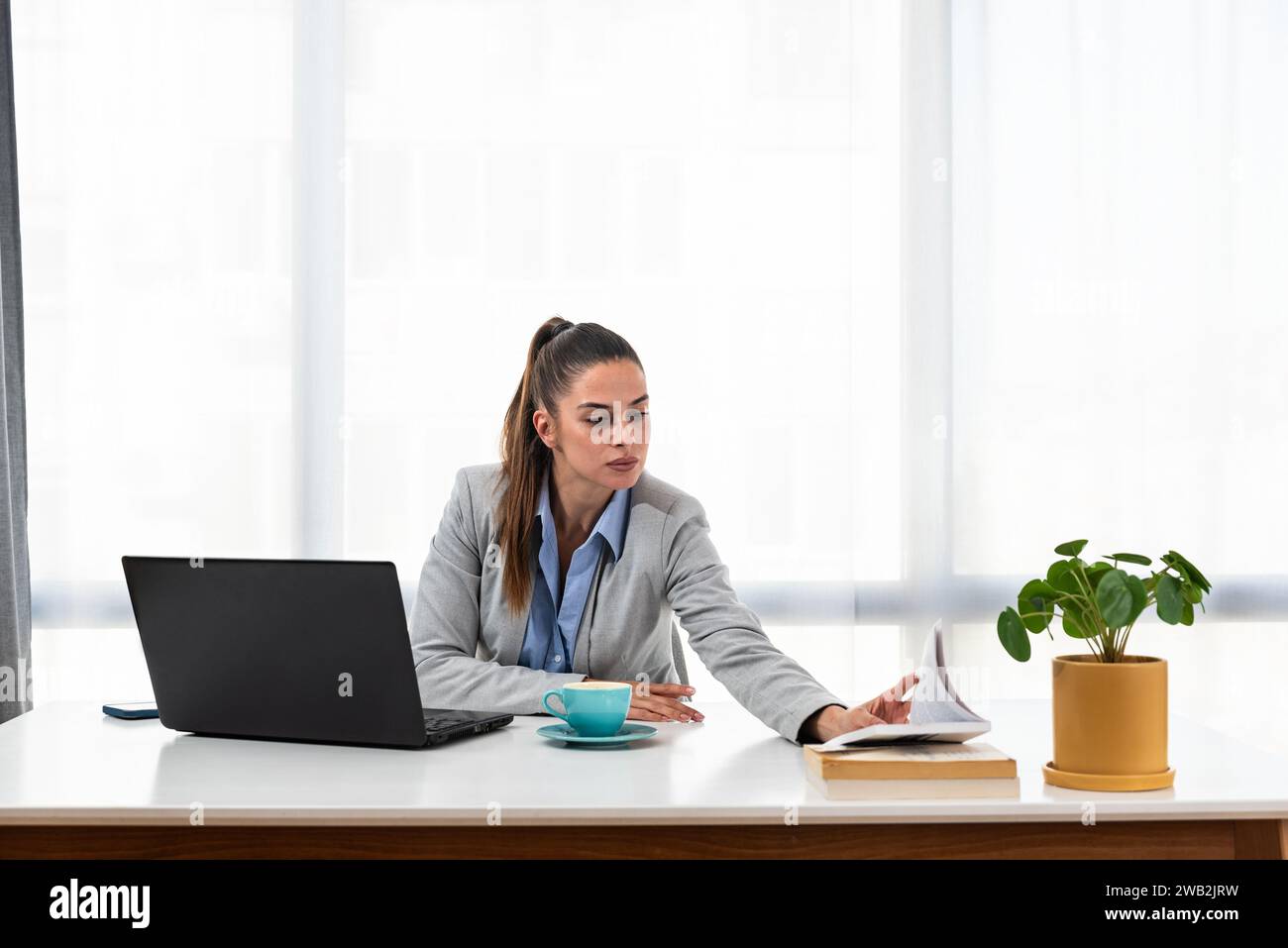 Giovane donna d'affari che si adatta al suo nuovo posto di lavoro dopo essere stata promossa a una posizione migliore in un nuovo ufficio in un'azienda globale. Foto Stock