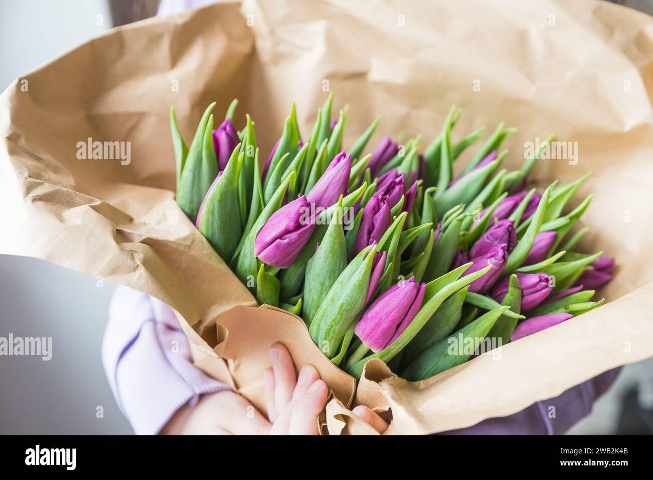 Tulipani colorati su carta artigianale. Tulipani gialli, rosa, magenta o fucsia su carta da imballaggio marrone. Tono disattivato. Decorazioni floreali per le vacanze primaverili. Foto Stock