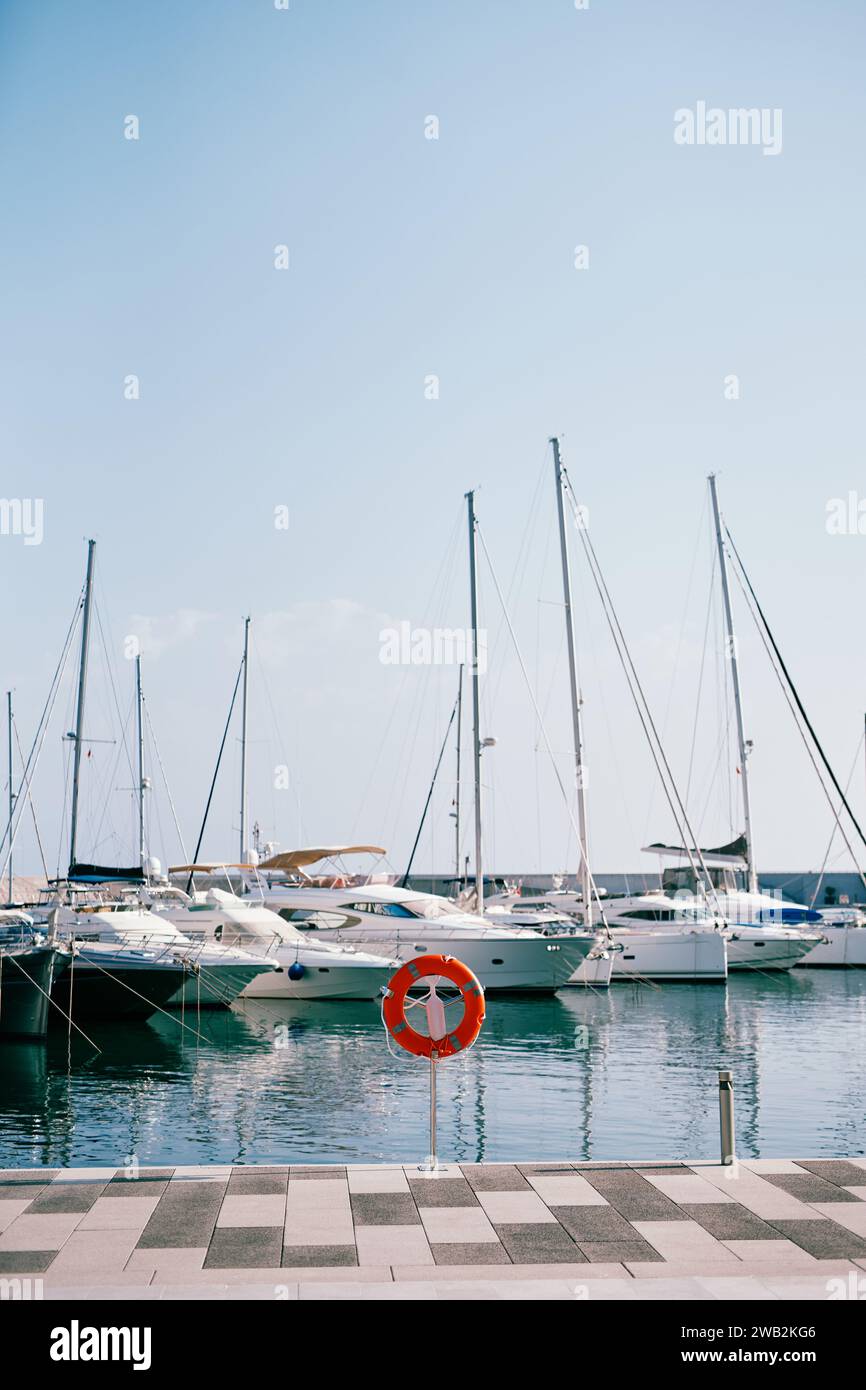 La Red Lifebuoy si erge su una tribuna sul molo sullo sfondo degli yacht ormeggiati Foto Stock