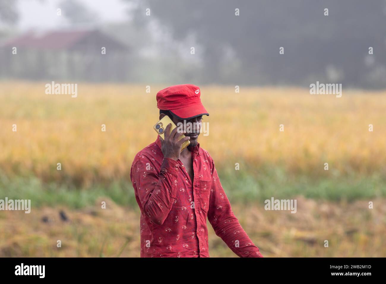 Chattogram, Bangladesh. 17 dicembre 2023. Un contadino parla su un cellulare vicino a gumai beel sulla rangunia upazila. SOLO PER USO EDITORIALE! Non per il settore commerciale Foto Stock