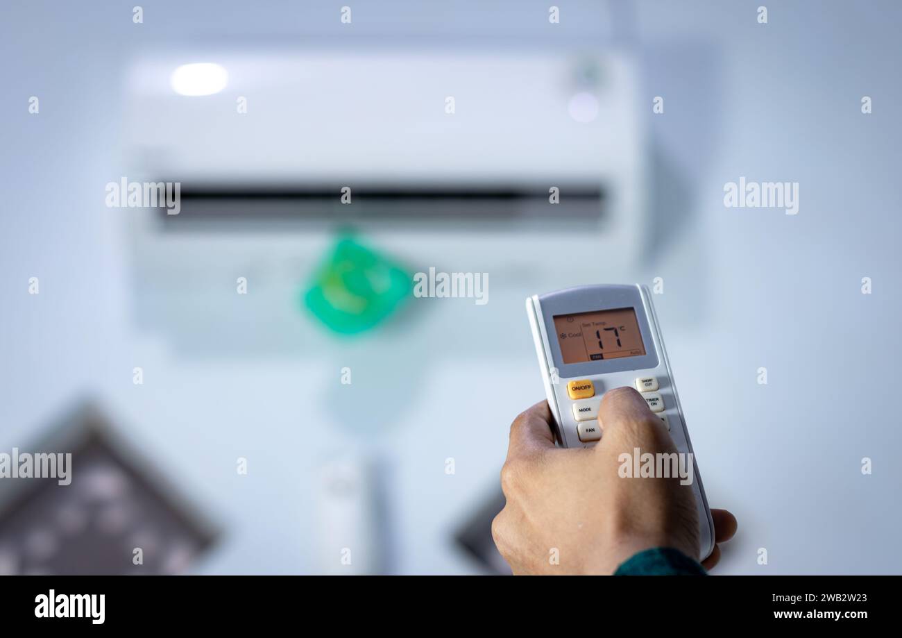 Mano dell'uomo con telecomando diretto al condizionatore. Foto Stock