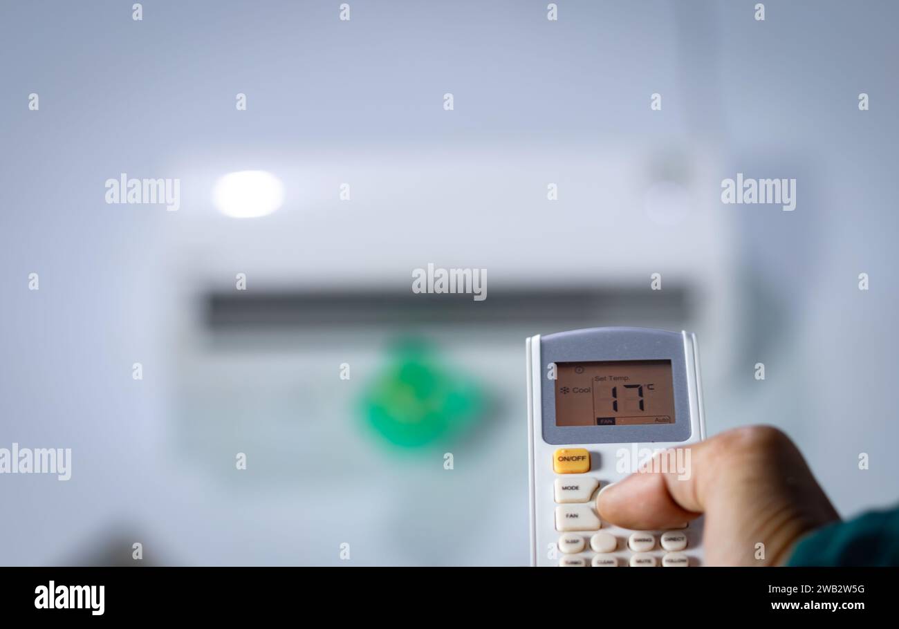 Mano dell'uomo con telecomando diretto al condizionatore. Foto Stock