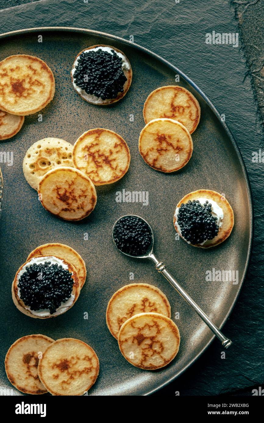 Blinis con caviale nero e formaggio cremoso, shot dall'alto, mini pancake, un elegante antipasto Foto Stock