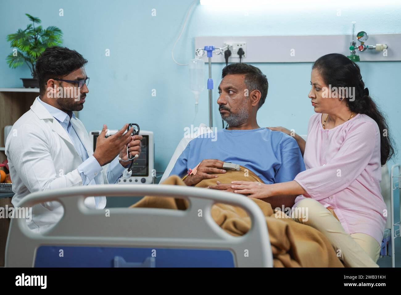 Medico indiano che spiega le condizioni di salute di uomo anziano a moglie in reparto ospedaliero - concetto di visita medica, consulenza professionale e assicurazione Foto Stock