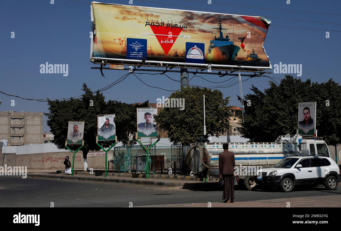 8 gennaio 2024, SANAA, Sanaa, Yemen: 8 gennaio, 2024, Sanaa, Yemen: un uomo cammina sotto un cartellone con un'immagine delle navi da guerra americane e parole in arabo che recitano: "la folla sarà sconfitta e volterà le spalle". gli Houthi hanno dichiarato la loro intenzione di bloccare i vascelli israeliani, o quelli di proprietà di compagnie israeliane, dal transito attraverso lo stretto di Bab al-Mandab fino a quando Israele cessa il suo assalto a Gaza. Nelle ultime settimane, gennaio, gli Houthi hanno intensificato i loro assalti alle navi mercantili con missili, droni e barche con droni. Questi attacchi hanno distrutto il flo Foto Stock