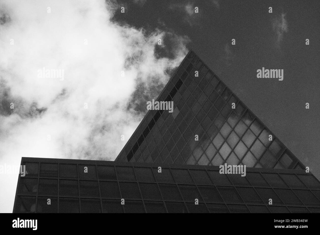 Splendida fotografia in bianco e nero che cattura il bordo nitido di un grattacielo contemporaneo contro un cielo dinamico, enfatizzando il contrasto tra ingegneria umana e bellezza naturale Foto Stock