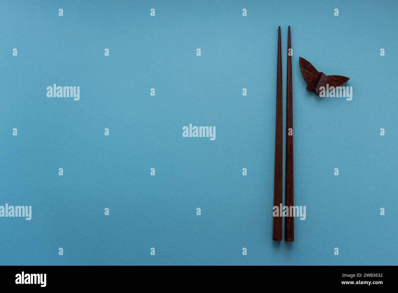 Coppia di bacchette di legno per piatti giapponesi e cinesi su sfondo blu con spazio per le copie. Concetto di viaggio e cucina. Natura morta minima Foto Stock
