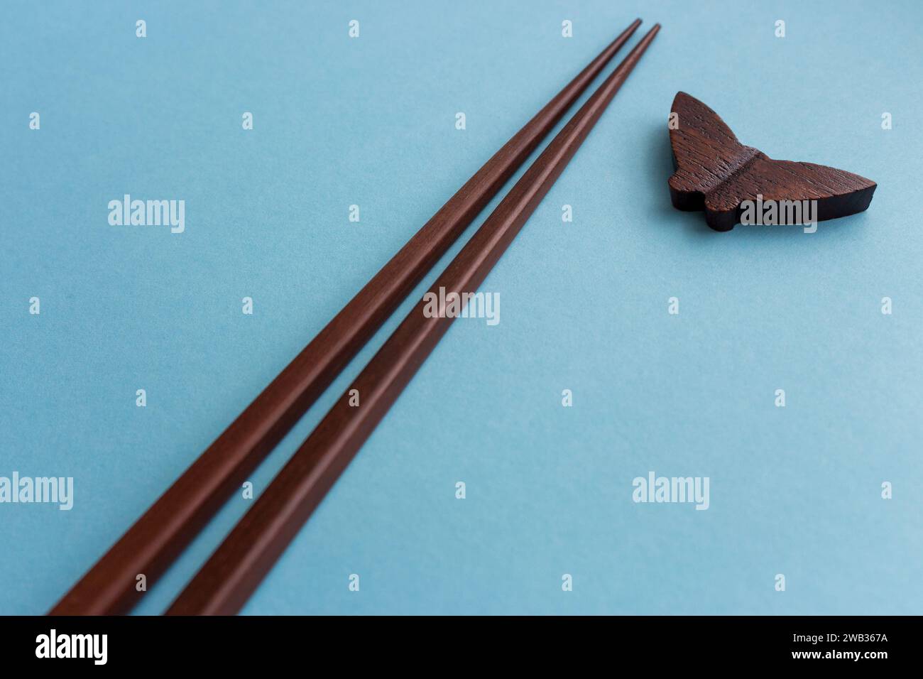 Coppia di bacchette di legno per piatti giapponesi e cinesi su sfondo blu con spazio per le copie. Concetto di viaggio e cucina. Natura morta minima Foto Stock