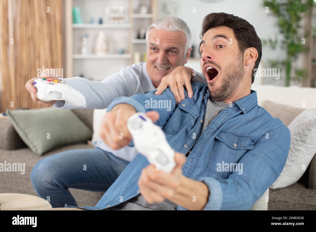 ortrait di due uomini eccitati che giocano a videogame a casa Foto Stock