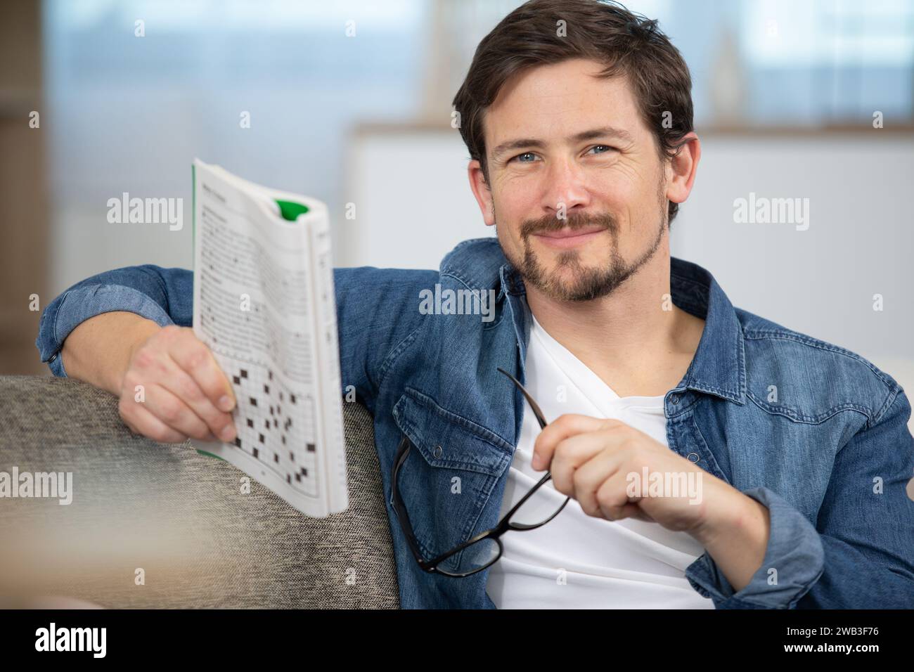 giovane uomo seduto facendo un puzzle crossword Foto Stock