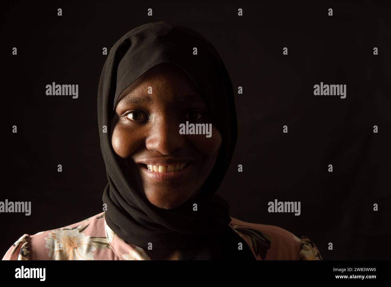 ritratto di una donna africana sorridente su sfondo nero Foto Stock