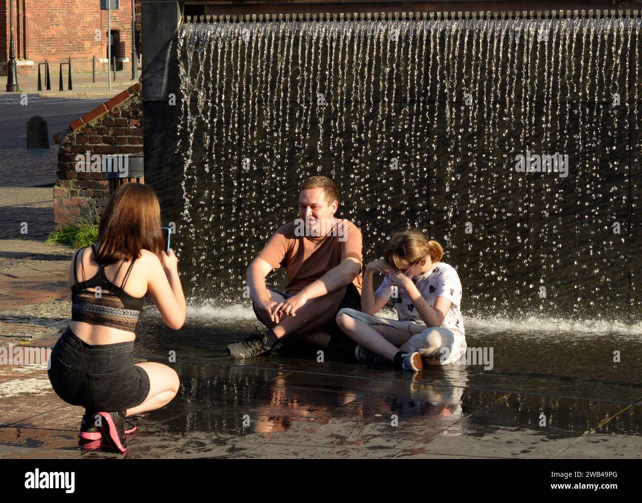 Gli adolescenti si divertono a scattare foto e bagnarsi in una fontana presso il Museo dell'Ambra di Danzica, Polonia, Europa, UE Foto Stock