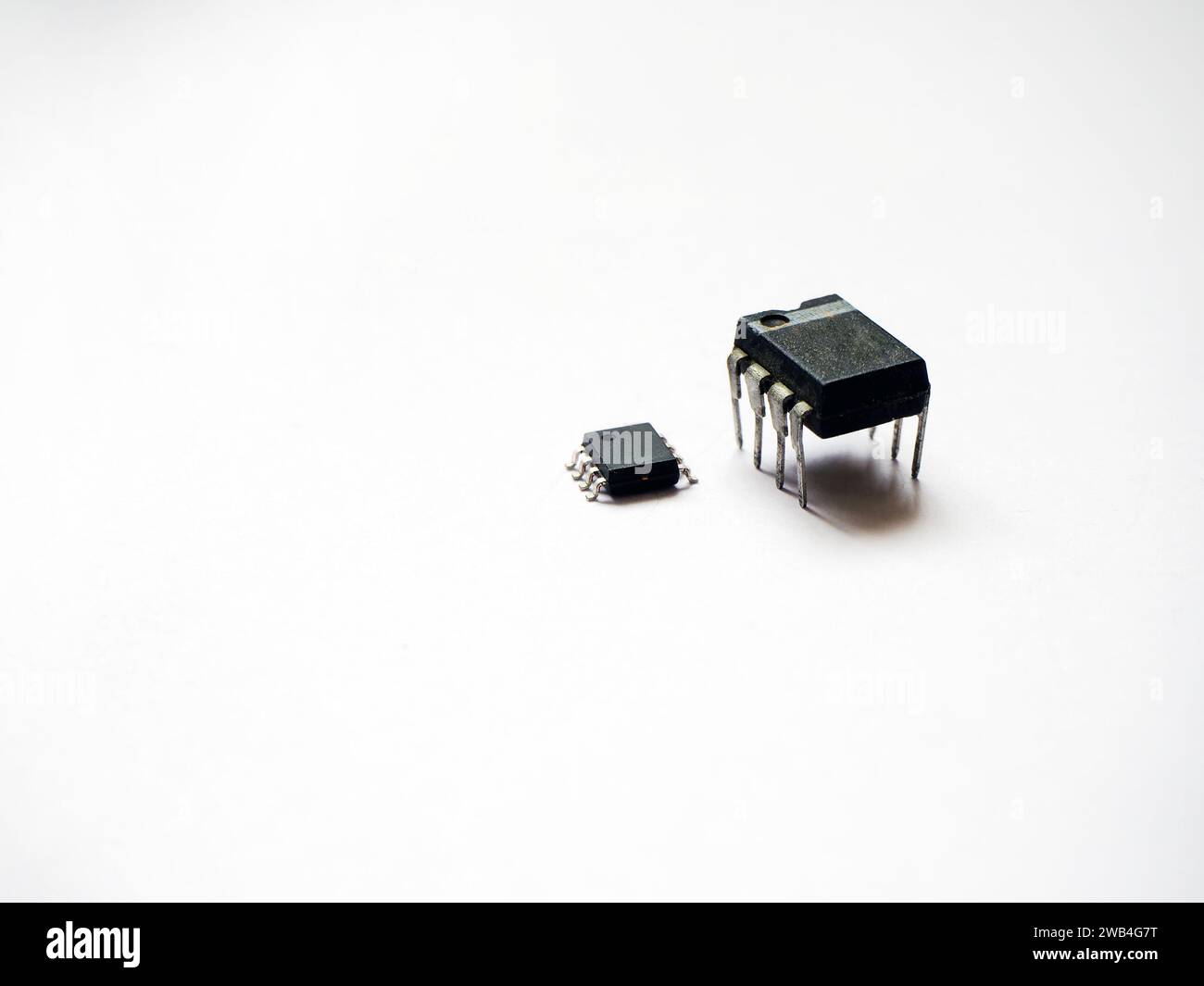 Componenti elettronici semiconduttori a foro passante e montaggio superficiale. Circuiti integrati a otto pin isolati su un bianco. Foto Stock