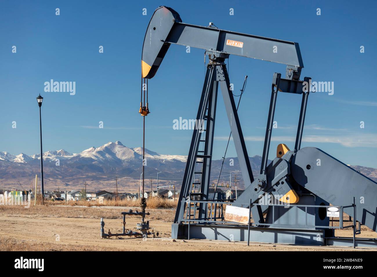 Frederick, Colorado - un pozzo petrolifero vicino a una suddivisione abitativa sul fronte del Colorado, con Mount Meeker e Longs Peak nella Rocky Mountain National Pa Foto Stock